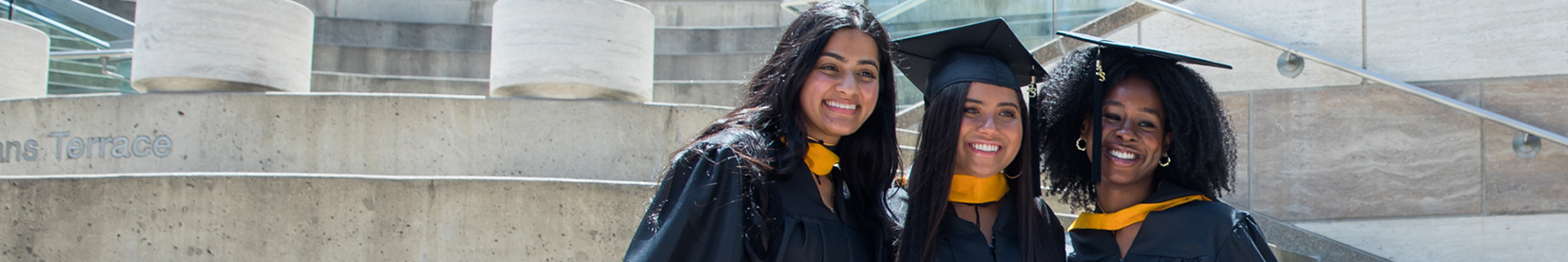 Three graduates posing in cap and gown
