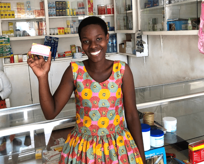 A member of the Malkia Klabu program in Tanzania, which provides HIV self-tests and contraceptives for adolescent girls and young women, shows off her loyalty card.